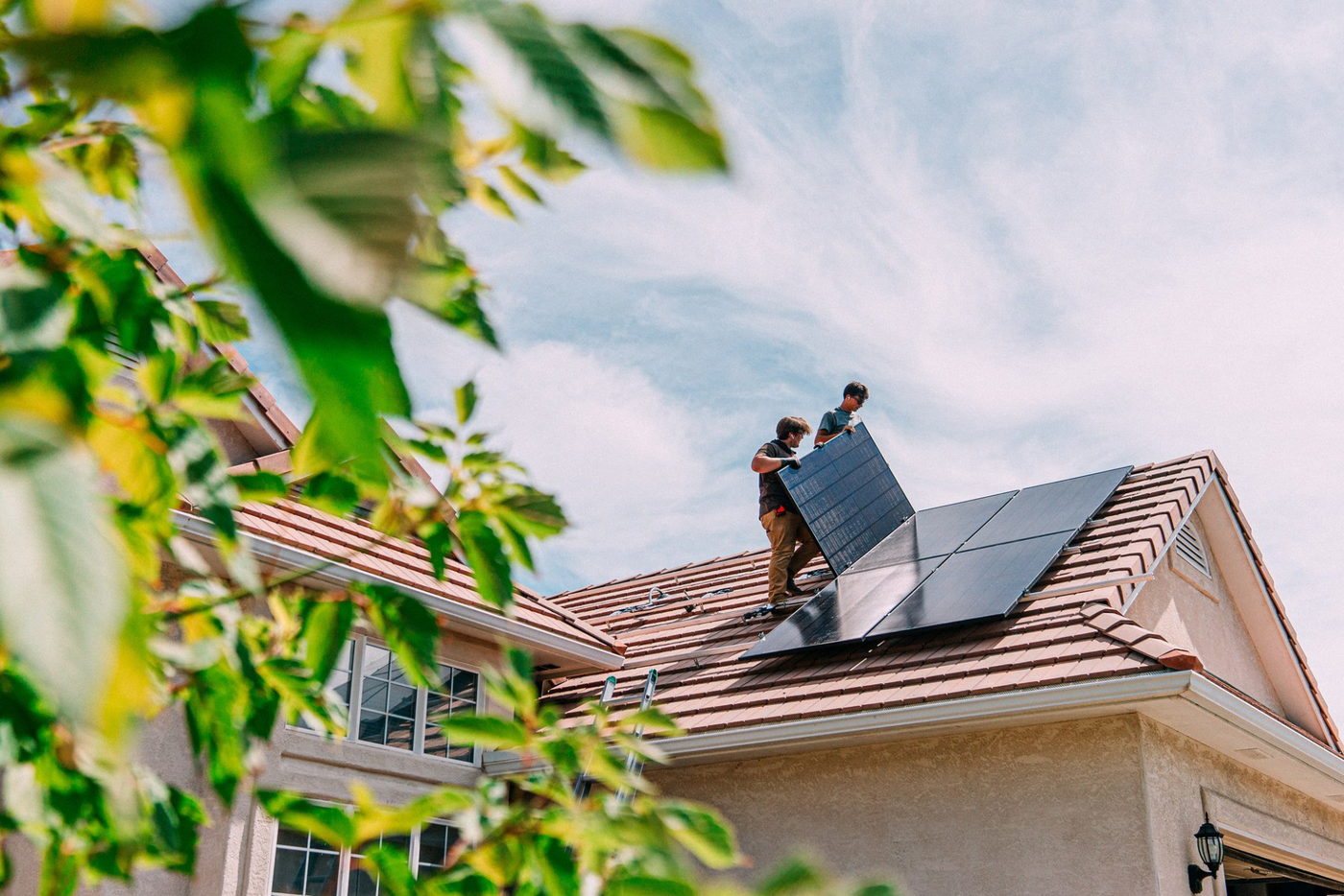 Installers fitting solar panels on a tiled roof